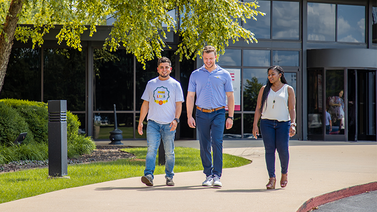  Three J.B. Hunt employees walking on a sidewalk outside of the J.B. Hunt corporate campus