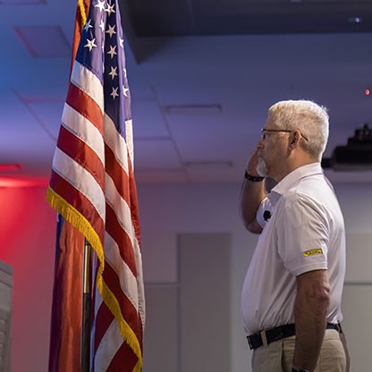 employee saluting flag at memorial day ceremony
