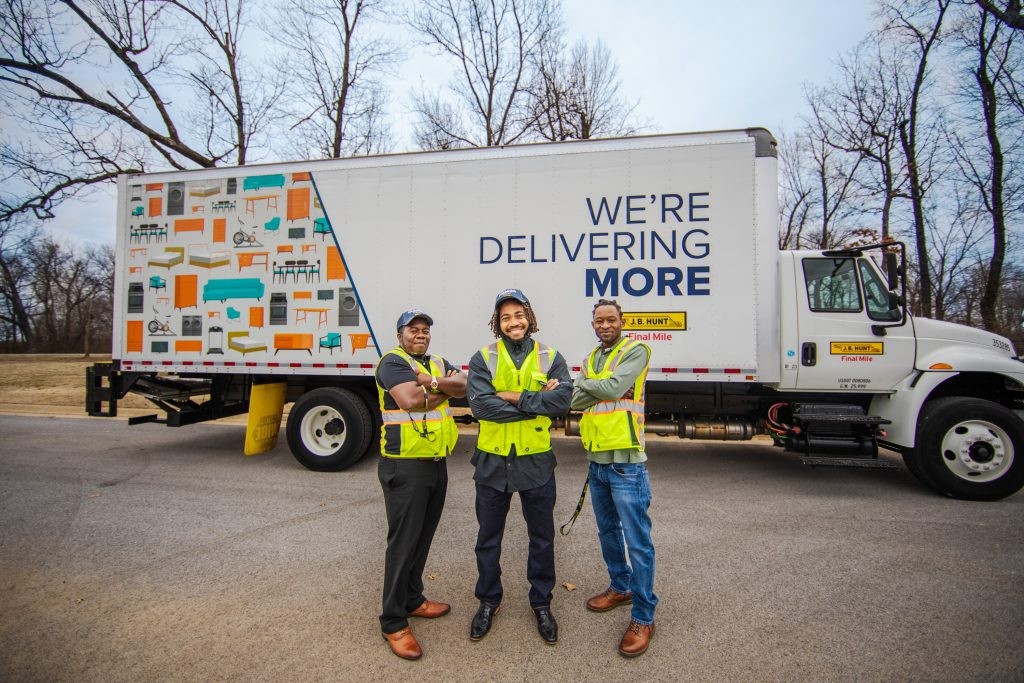 Three J.B. Hunt warehouse employees standing beside a box truck.