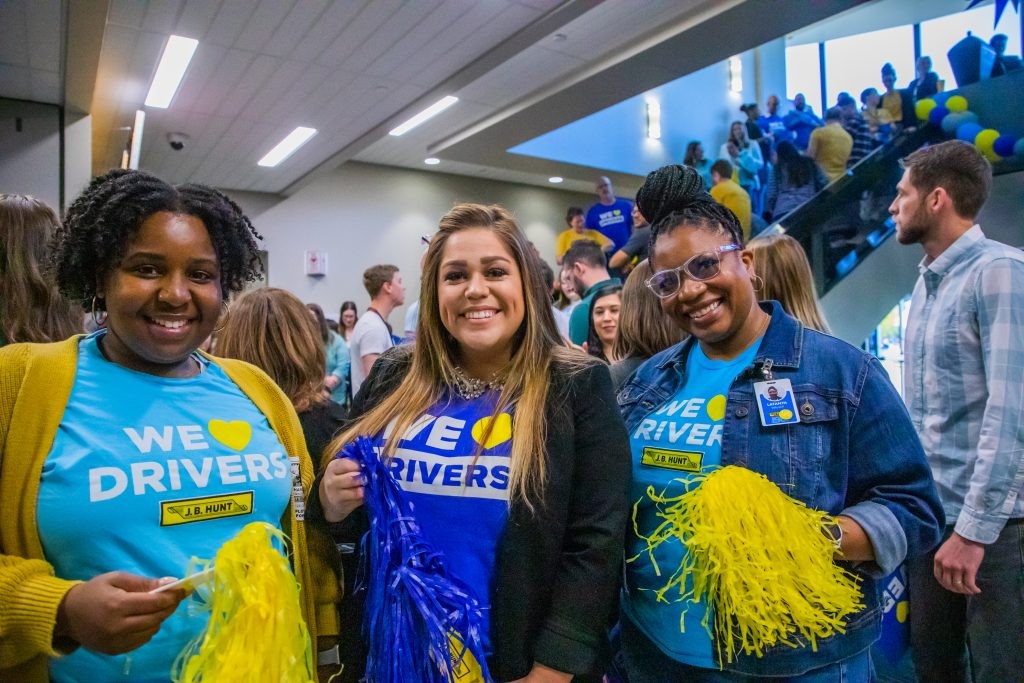 Three J.B. Hunt employees posing in front of a staircase in the J.B. Hunt main office during a driver appreciation event