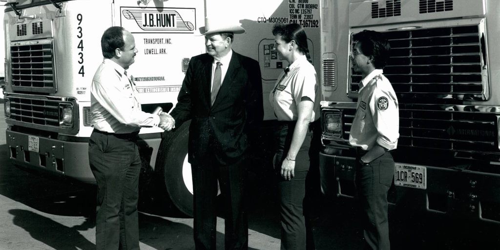J.B. Hunt shaking hands in front of J.B. Hunt trucks