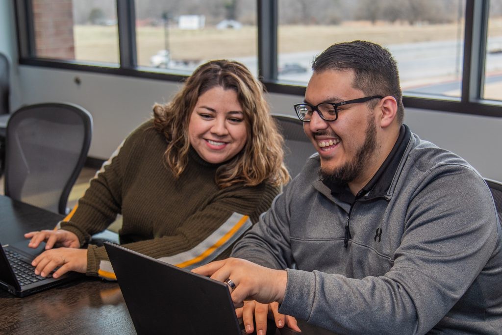 Two J.B. Hunt employees smiling and looking at laptops
