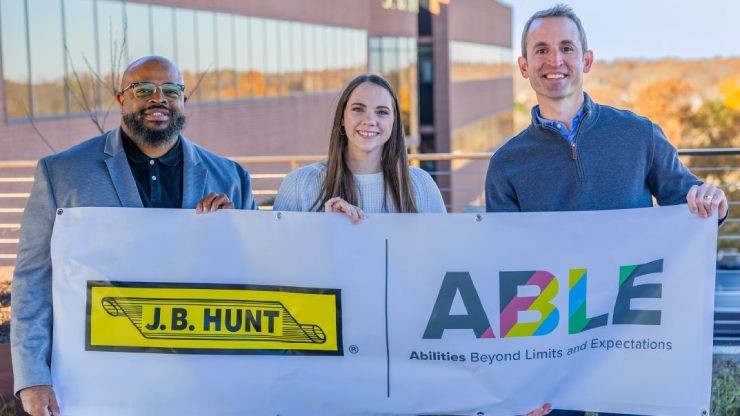ABLE Board Members with ABLE and J.B. Hunt Banner Three ABLE ERG board members holding a banner displaying the J.B. Hunt logo and ABLE slogan “Abilities Beyond Limits and Expectations” outside company headquarters.
