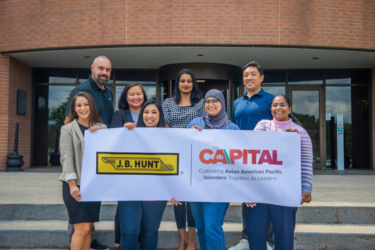 A group of CAAPITAL ERG members holding a banner with a CAAPITAL logo.