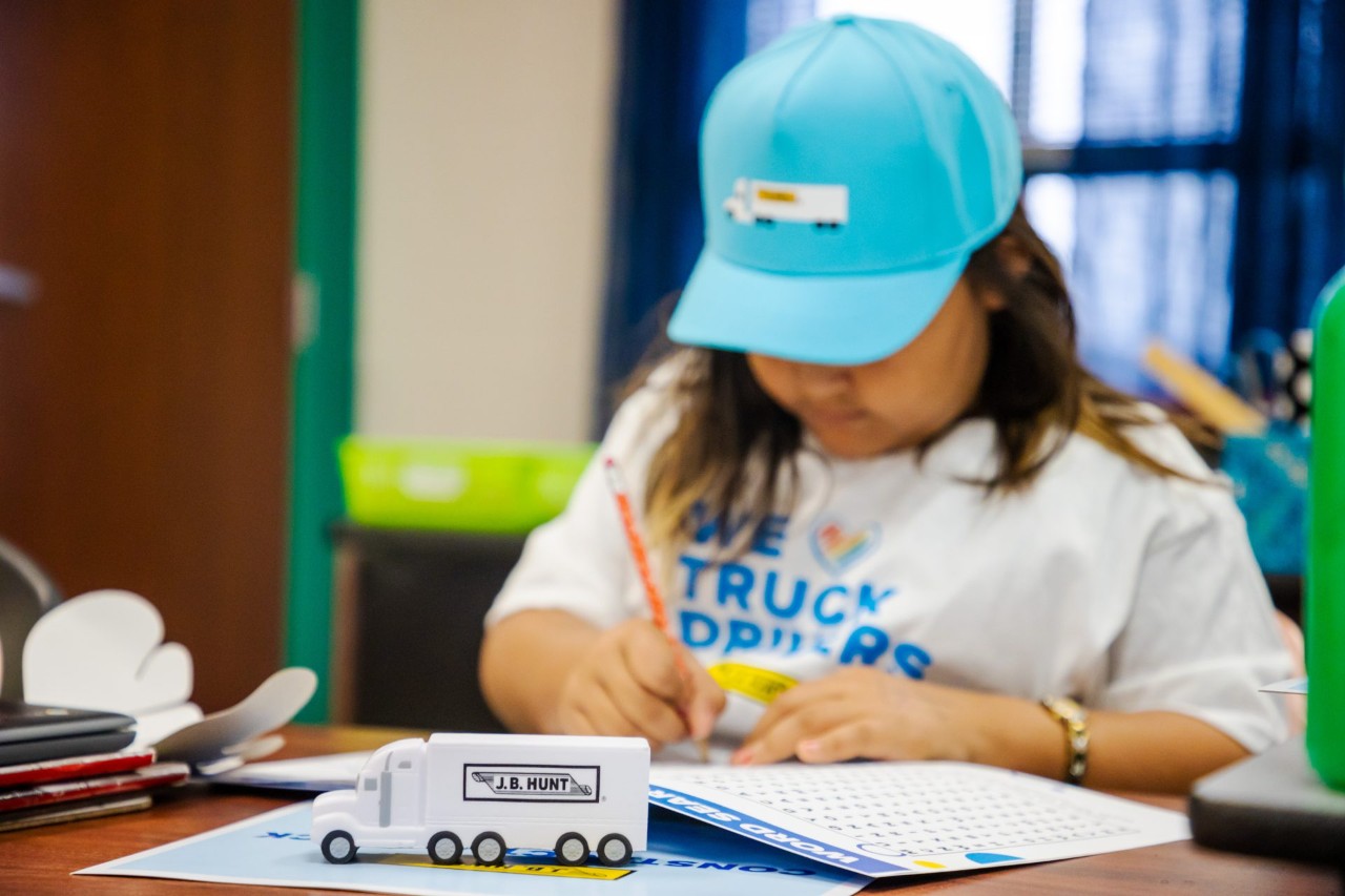 A student of the Adopt a Class classroom writing in a notebook.