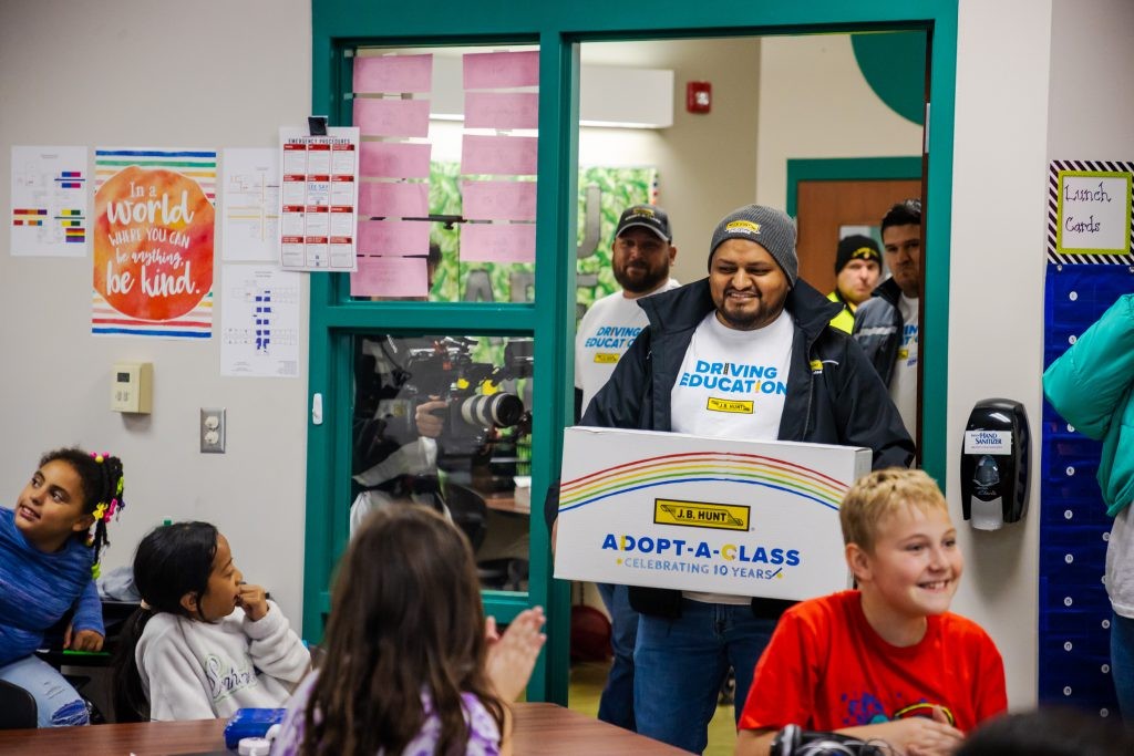 J.B. Hunt drivers carries an Adopt-a-Class box into a classroom.