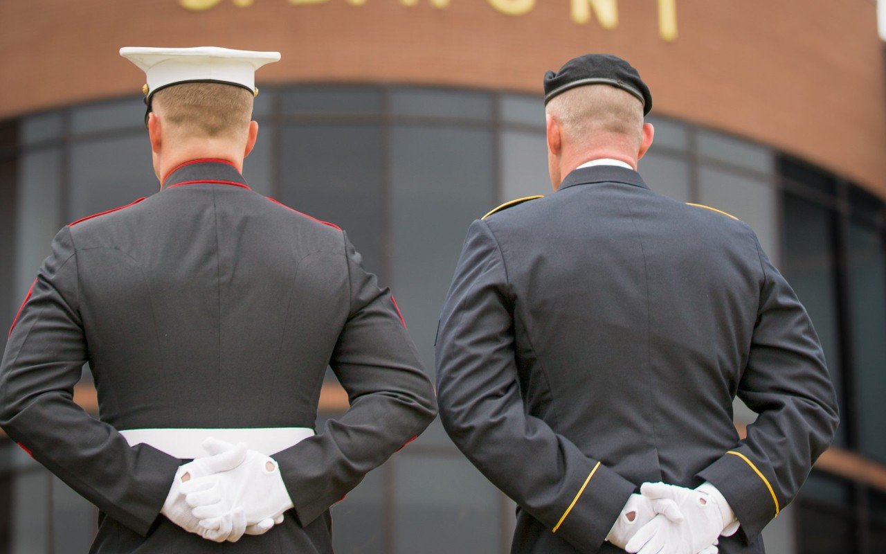 Two military members with their arms behind their backs.
