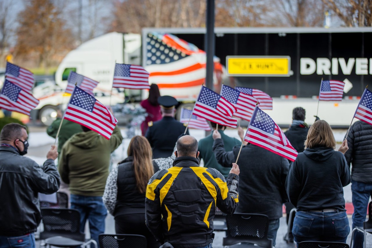 People holding American flags at a Wreaths Across America event.
