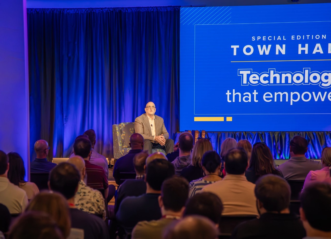 Stuart Scott speaking on stage at a corporate town hall.