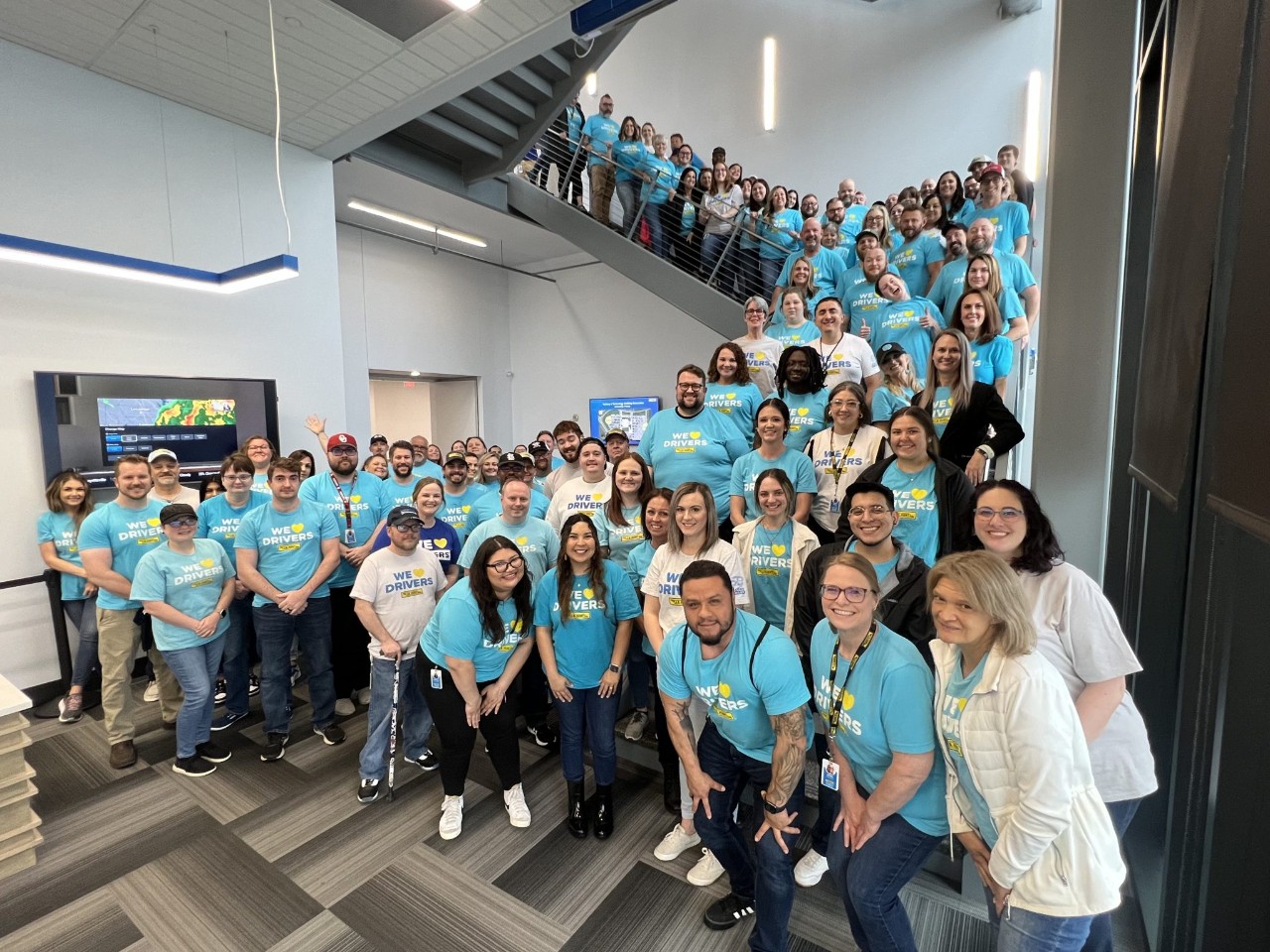 group photo of J.B. Hunt employees wearing blue shirts standing on stairs