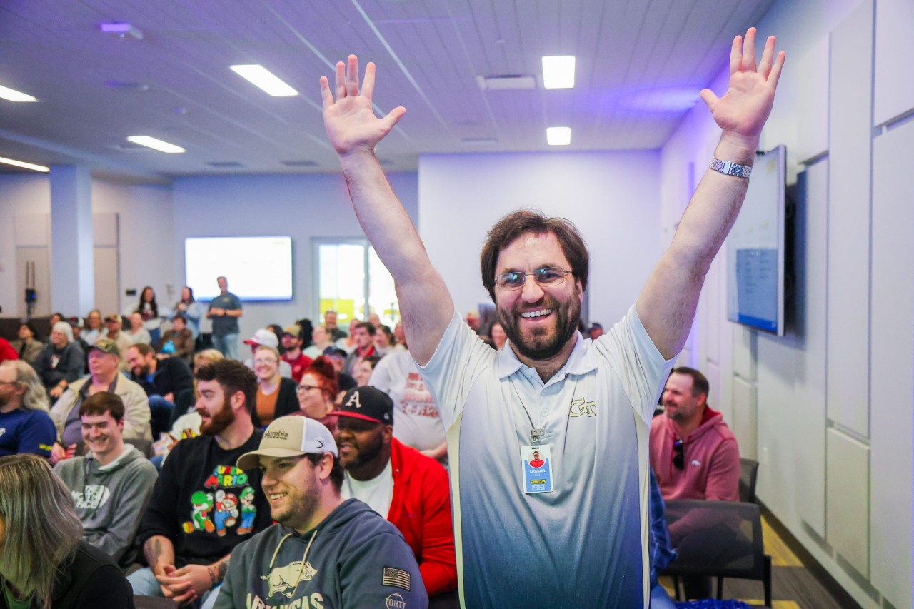 man wearing glasses holding up his hands cheering