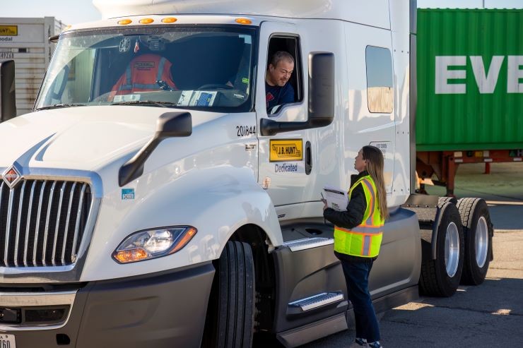 A J.B. Hunt driver leaning his head out the window to speak to a trainee.