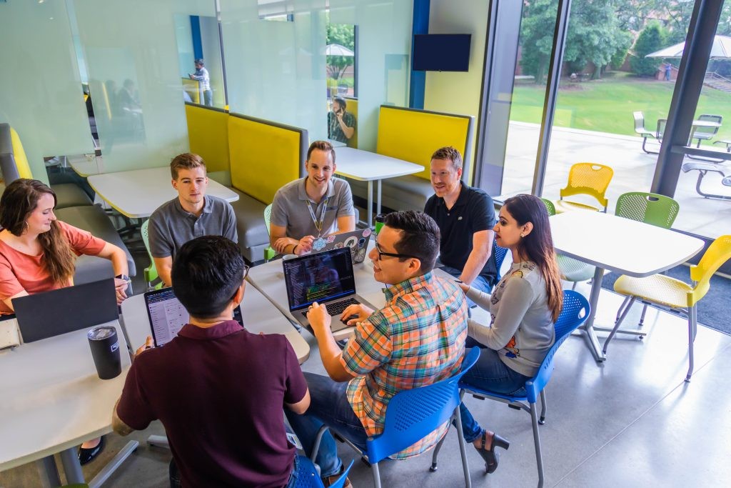 A group of J.B. Hunt employees conversing around a table.