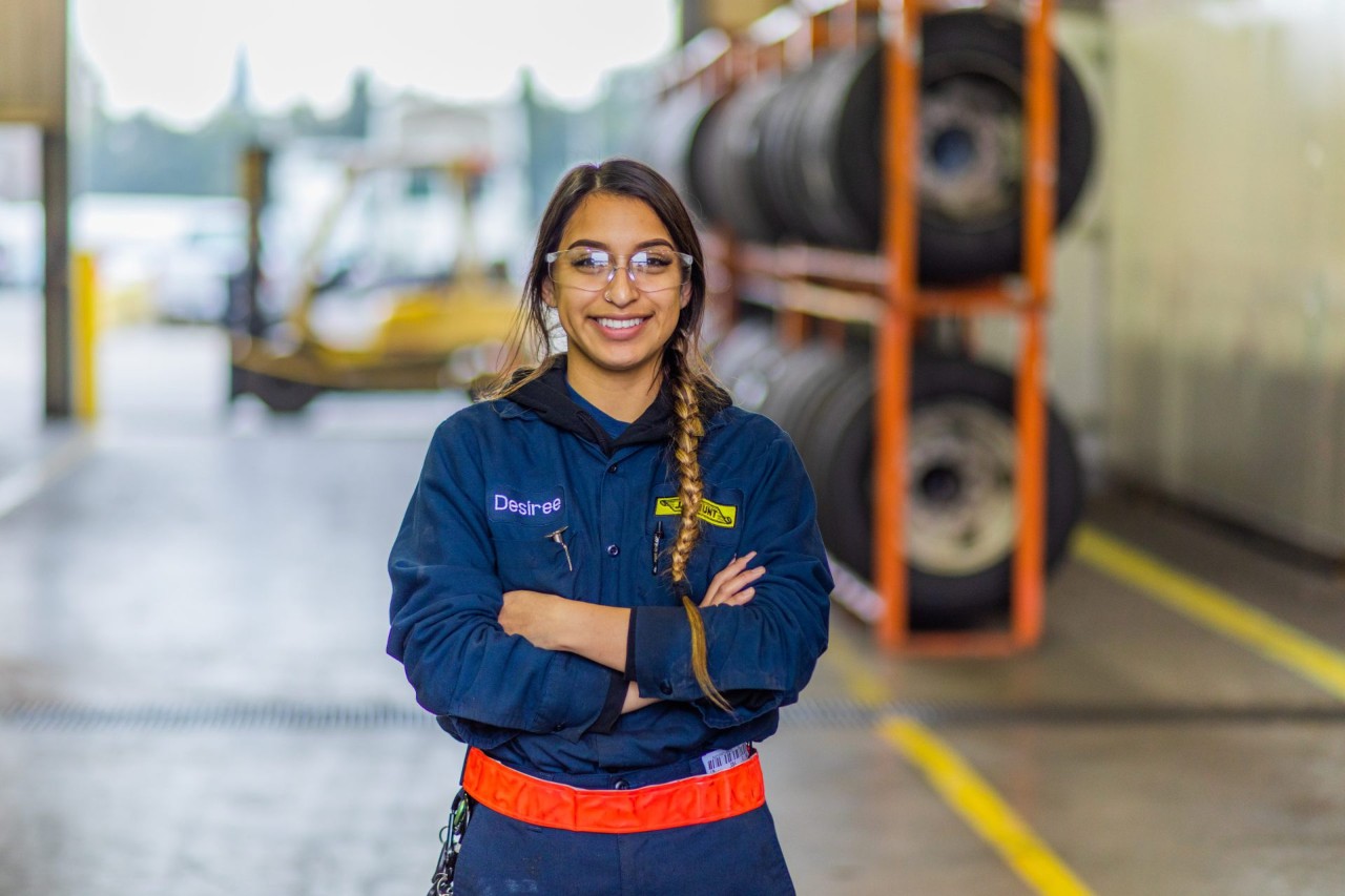 Maintenance employee, Desiree, posing for a photo in a maintenance shop.