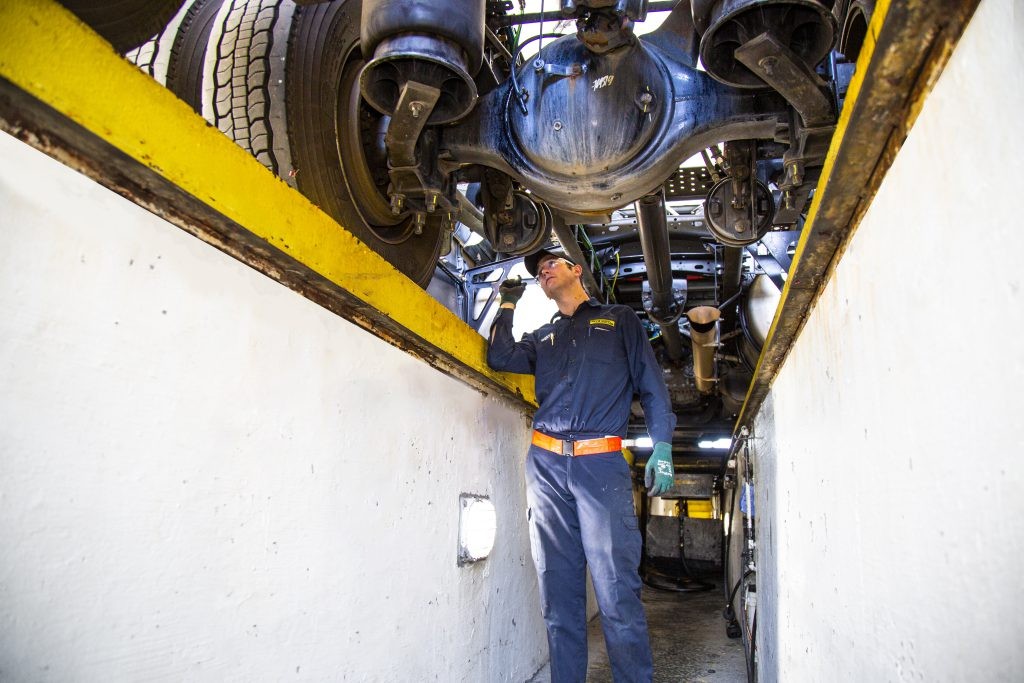 J.B. Hunt maintenance tech checking underside of truck
