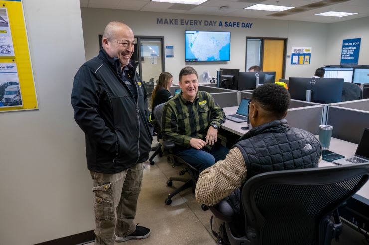 Three J.B. Hunt field employees speaking on the main office floor.