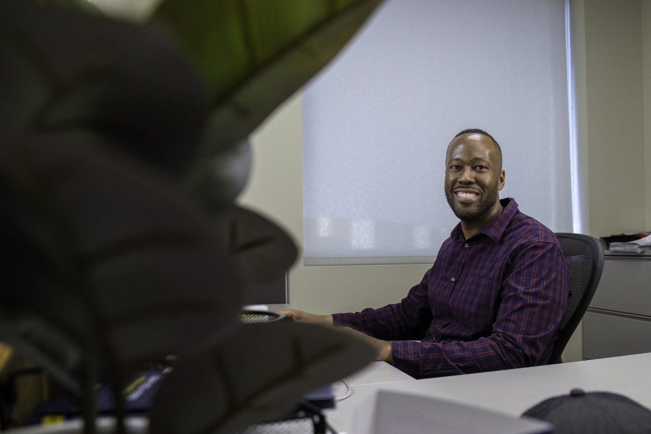 Man sitting at his desk smiling at the camera.