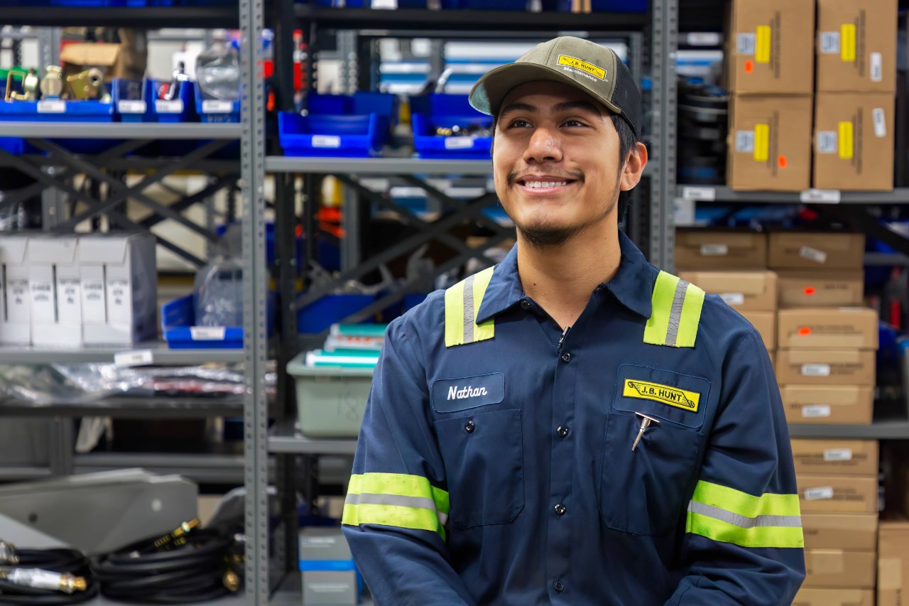 J.B. Hunt technician smiling while on an on-camera interview at equipment in our Joliet, Illinois shop.