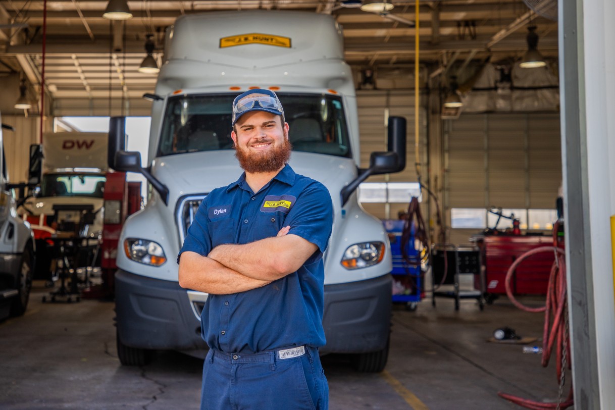 Dylan standing outside of a maintenance bay with arms crossed and smiling.