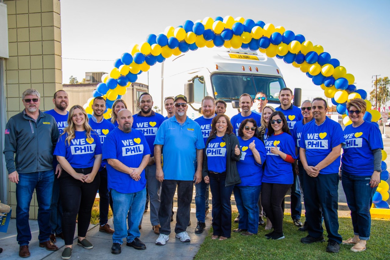 A group of J.B. Hunt employees with "We Love Phil" shirts in celebration of Phil, a 5 million safe mile driver.