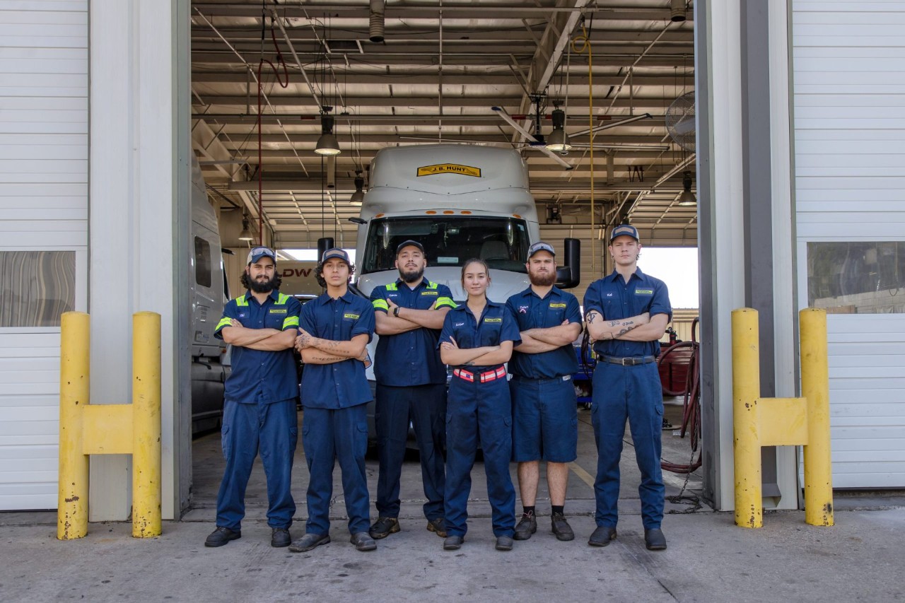 A group of maintenance employees standing in front of a maintenance bay.
