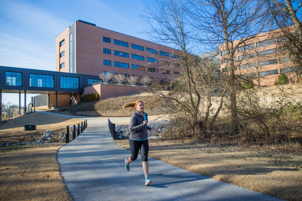 A woman jogging along the trail around the J.B. Hunt corporate campus.