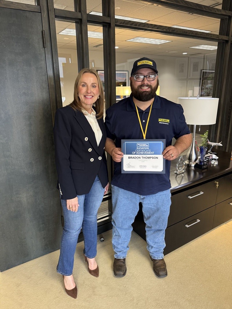 Bradon standing with Shelley Simpson while holding up his Elevation certificate