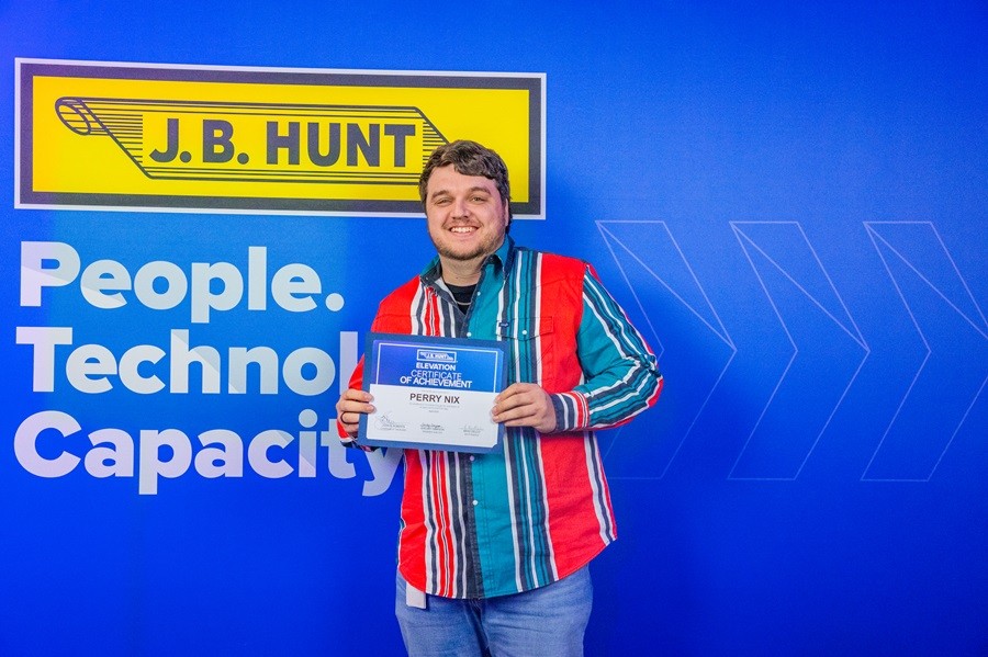 J.B. Hunt employee pointing at their name on the Elevation wall.