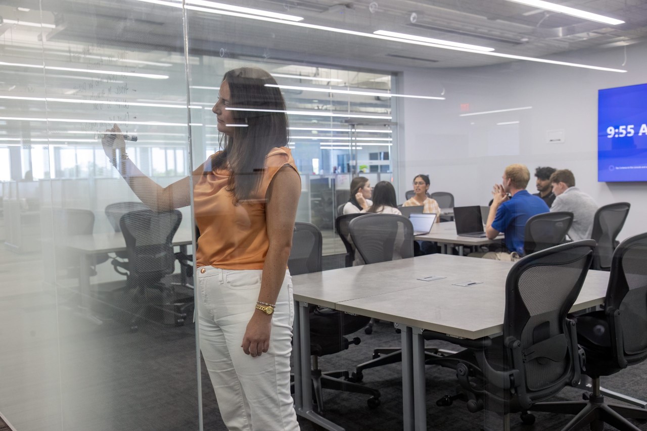 Woman writing on a glass wall in a meeting room.