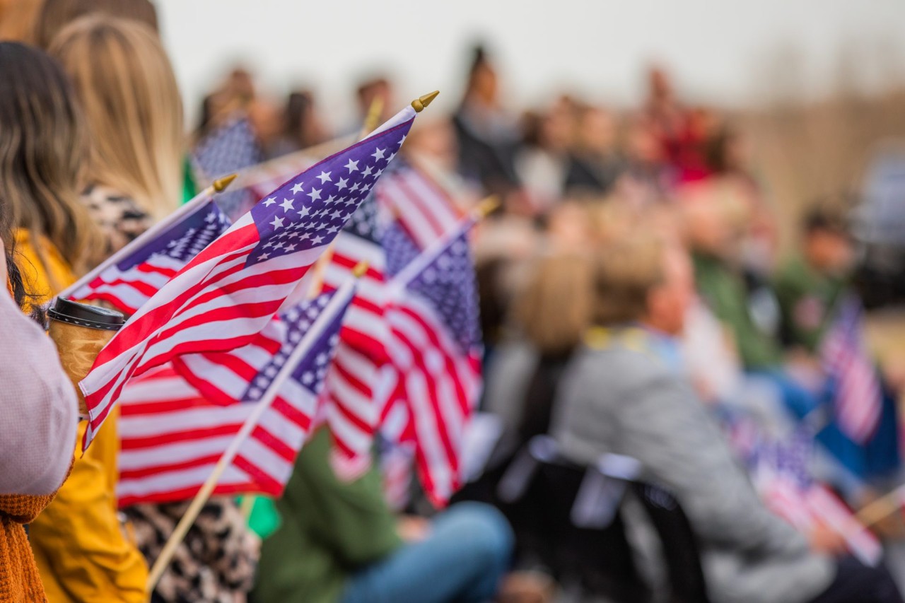 People holding American flags at a military event.