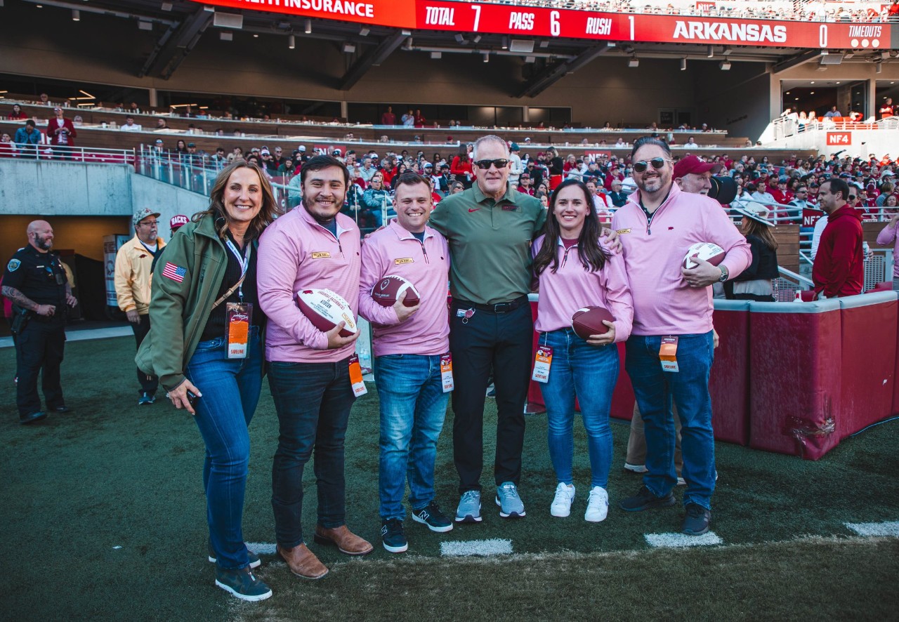 J.B. Hunt veteran employees being honored on the field of an Arkansas Razorbacks football game. Pictured with J.B. Hunt President, Shelley Simpson, and University of Arkansas Athletic Director, Hunter Yurachek.