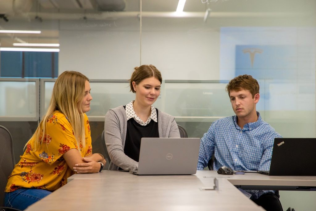 Three J.B. Hunt employees working on a laptop in a conference room