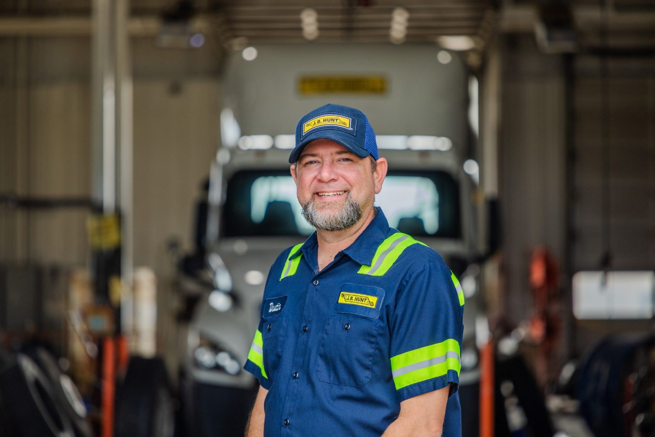 A maintenance technician standing in front of a maintenance bay.