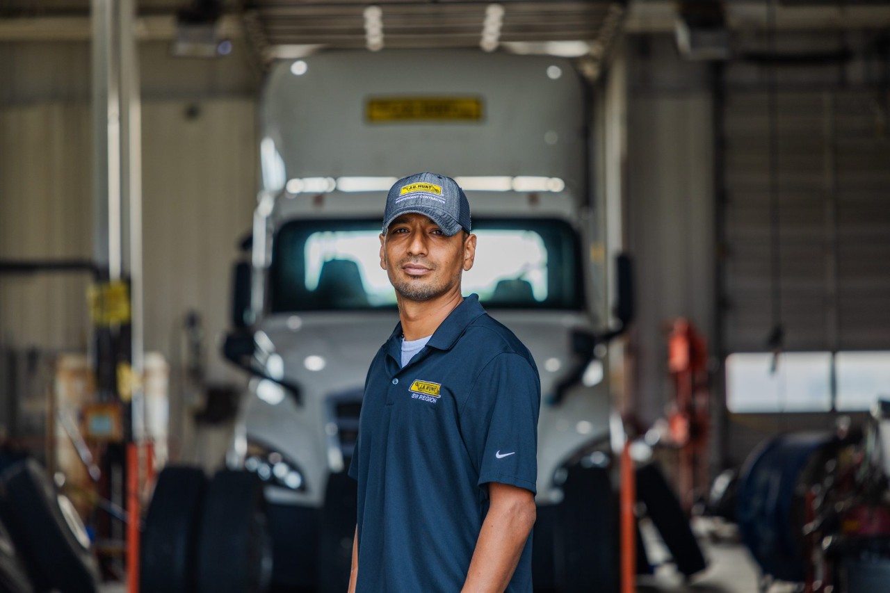 A maintenance technician standing in front of a maintenance bay.