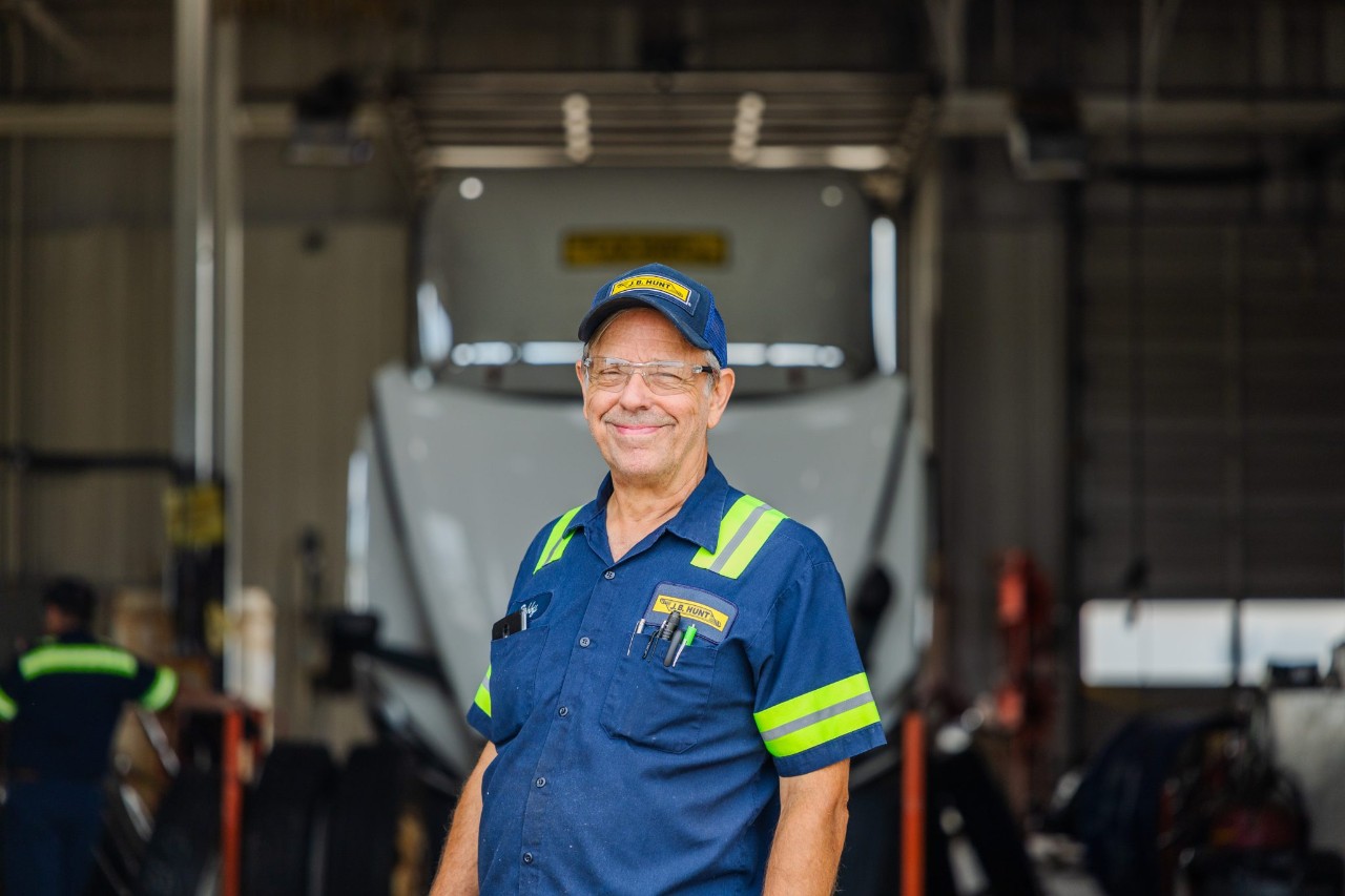 A maintenance technician standing in front of a maintenance bay.