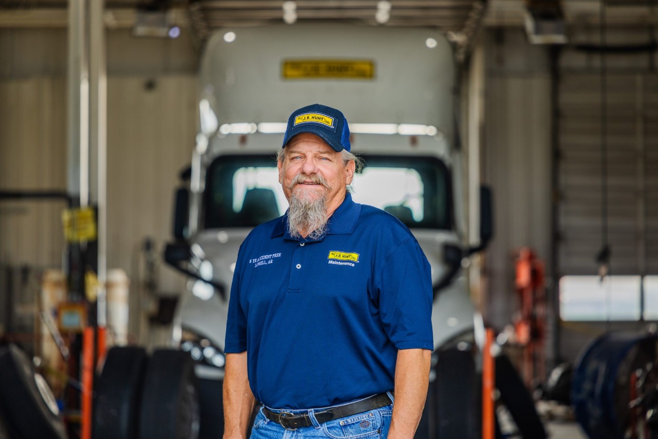 A maintenance technician standing in front of a maintenance bay.