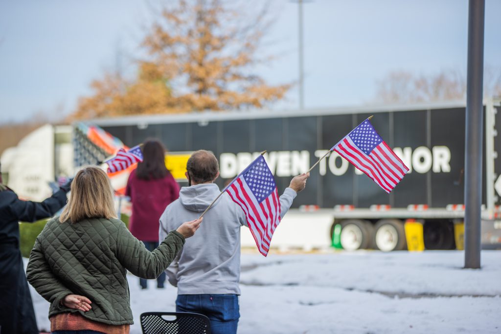 J.B. Hunt employees hold flags at Wreaths Across America ceremony.