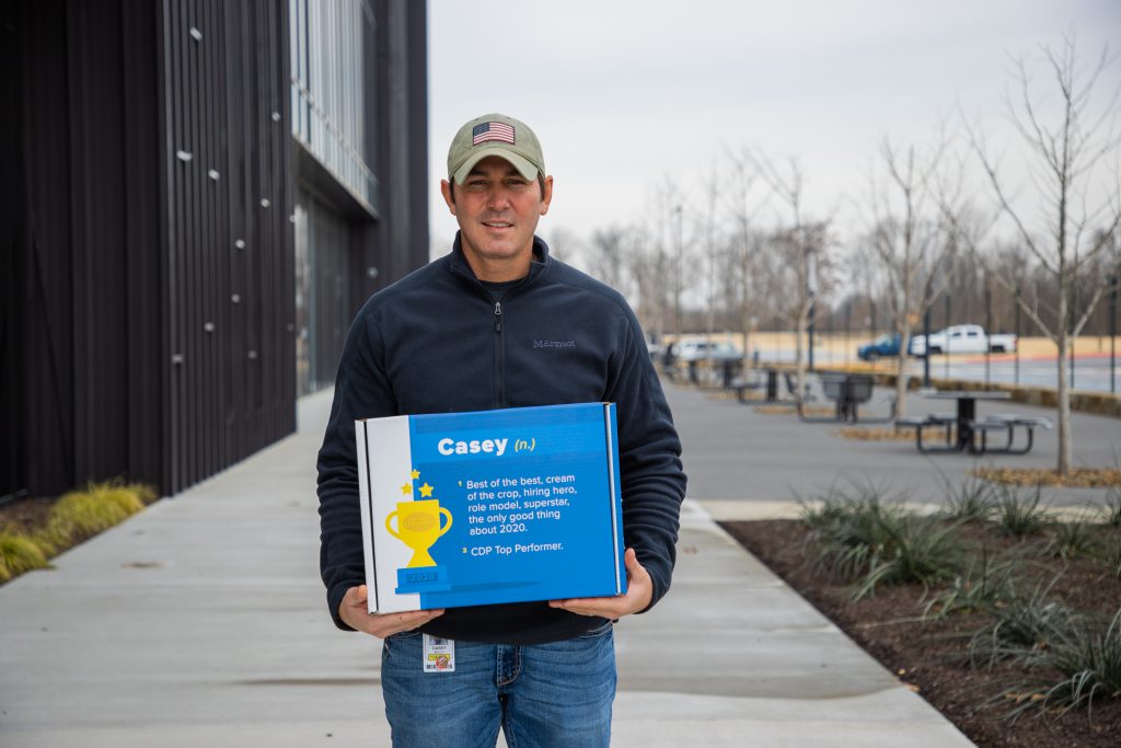 CDP employee, Casey, holding a Top Performer award box outside J.B. Hunt Technology building.