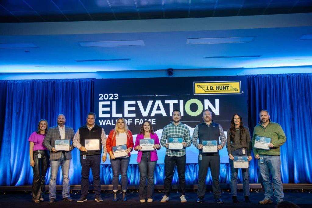 Nine J.B. Hunt employees stand on stage holding awards.