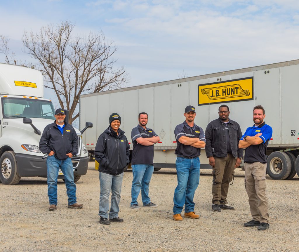 J.B. Hunt technicians stand in front of J.B. Hunt branded semi-truck and trailer.