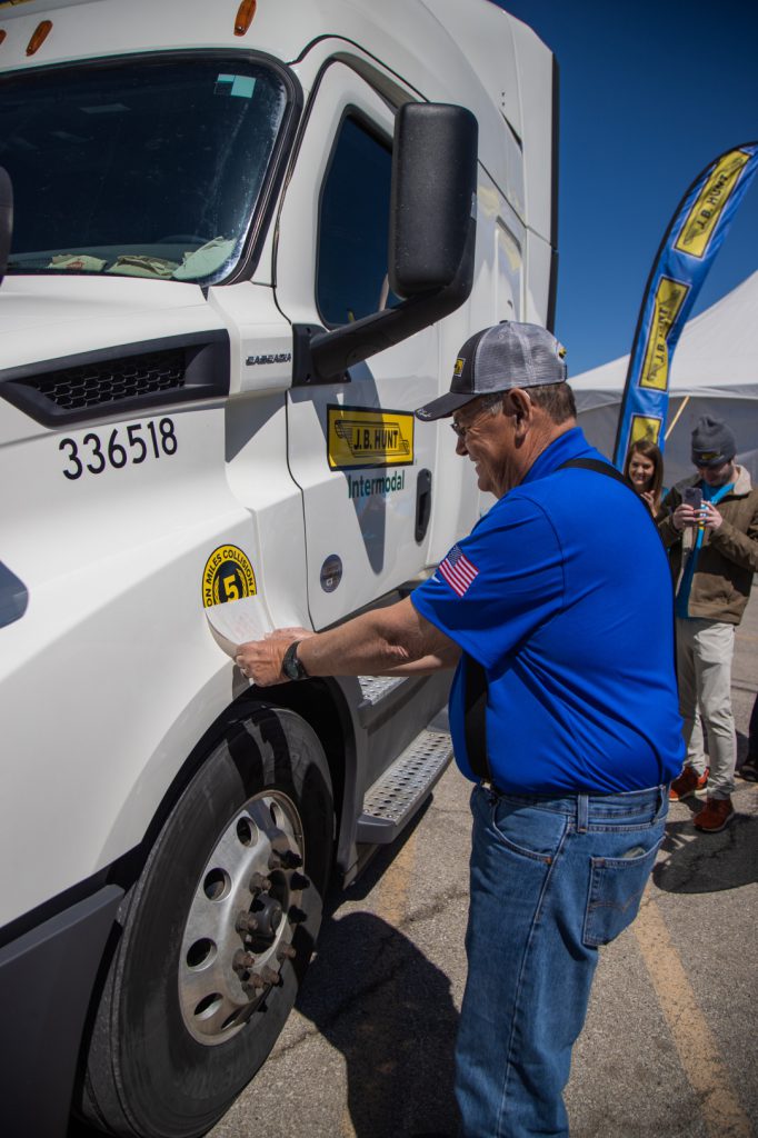 J.B. Hunt driver, Chuck Barrett, putting his five million safe miles sticker on his truck. 