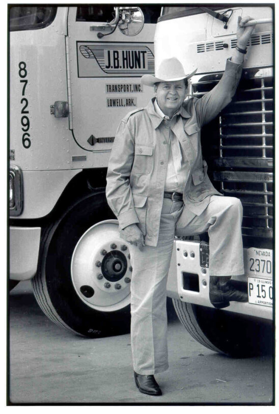 J.B. Hunt founder, Johnnie Bryan Hunt, standing in front of a fleet of J.B. Hunt trucks.