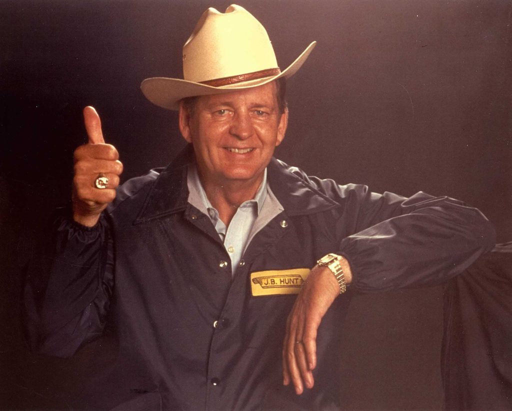 Johnnie Bryan Hunt smiling and giving a thumbs up in his famous white cowboy hat.