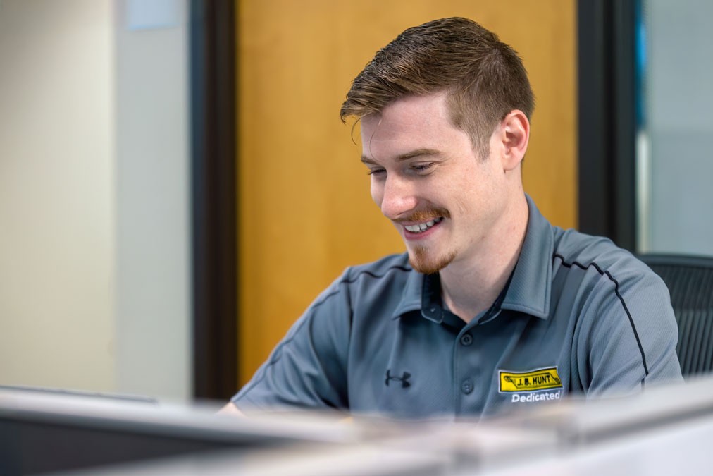 smiling entry-level employee sitting at desk 