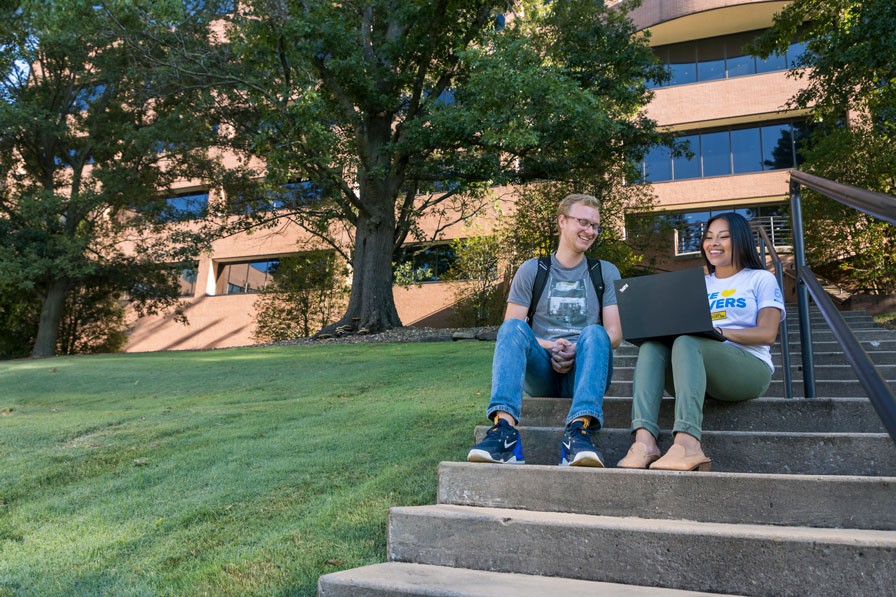 two entry level employees talking outside on the stairs