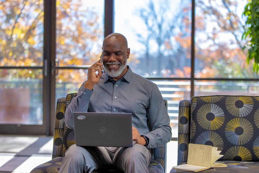 man sitting in lobby with laptop on the phone