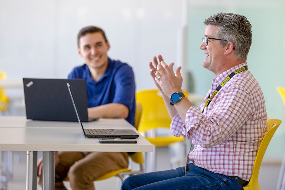 man with laptop in front of him talking to other people in a meeting