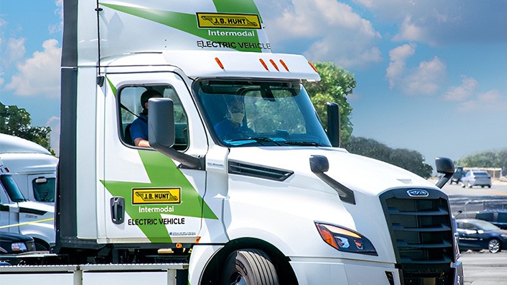 A white J.B. Hunt electric truck in a parking lot on a sunny day