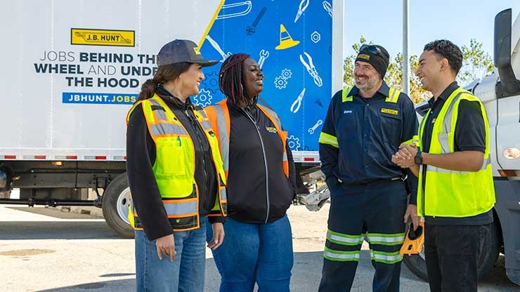 group of j.b. hunt employees talking outside near trucks